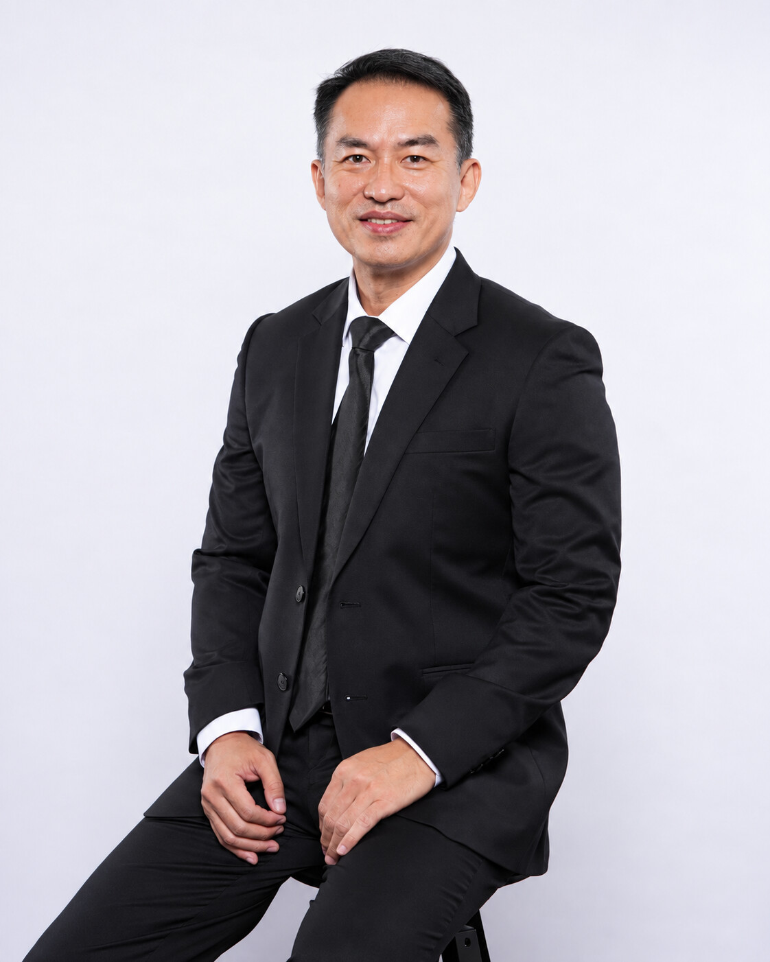 Herwan Ng seated in a dark suit and black tie